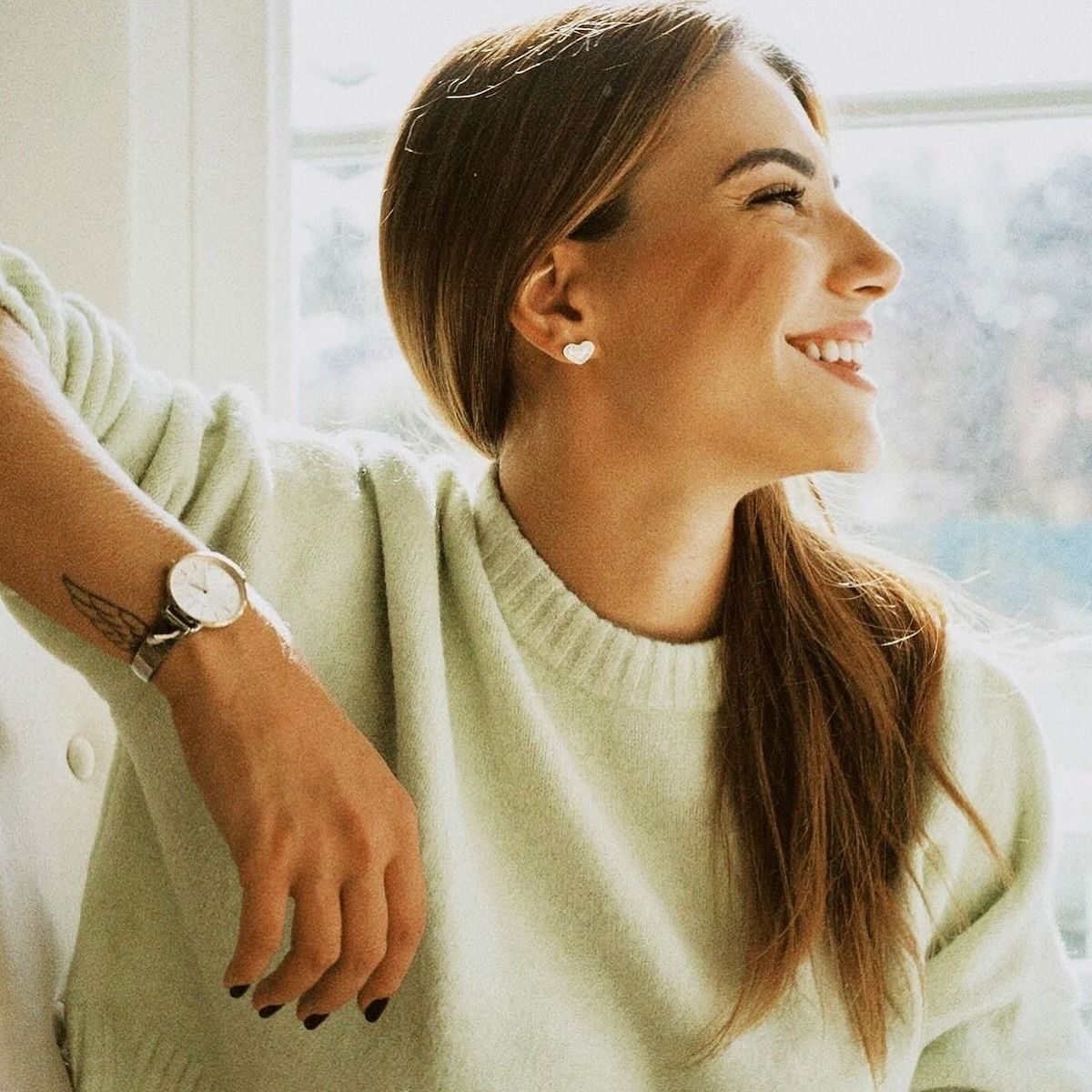 Carolina Carvalho smiling, watch on her wrist, dark nails